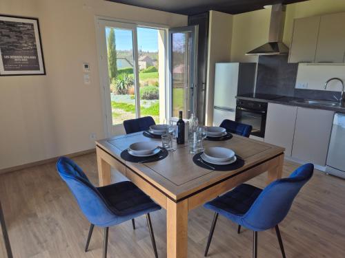 a kitchen with a wooden table and blue chairs at Maison paisible et agréable in Salles-Curan