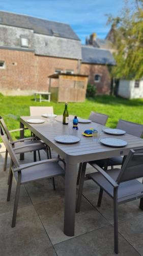 een grijze tafel met stoelen en een fles wijn bij Maison avec jardin et parking gratuit in Étretat