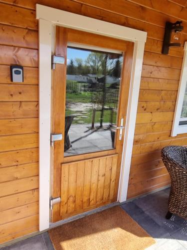 a door to a cabin with a dog looking through it at Nieuw - Luxe Blokhut Chalet in bosrijke omgeving in Anloo