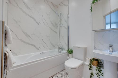 a white bathroom with a toilet and a sink at Stylish Modern Town Centre Flat in Carterton