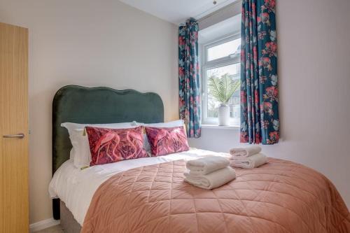 a bedroom with a bed with two towels on it at Stylish Modern Town Centre Flat in Carterton