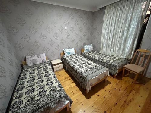 una habitación con 3 camas y una silla. en SeMa Qonaq Evi, en Zaqatala