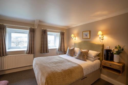 a bedroom with a large bed and two windows at The Pheasant Inn in Falstone