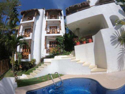 a building with a swimming pool in front of a house at Mar y Sueños Suites in Sayulita