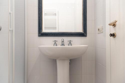 a white sink in a bathroom with a mirror at Bolgheri Countryhouse in Bolgheri