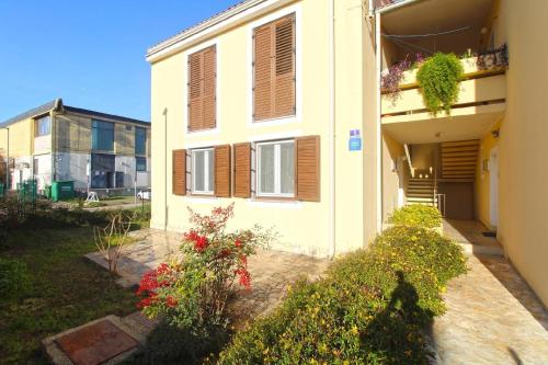 ein weißes Gebäude mit braunen Fensterläden und Blumen in der Unterkunft Studio für 4 Personen ca 48 qm in Fažana, Istrien Istrische Riviera in Fažana