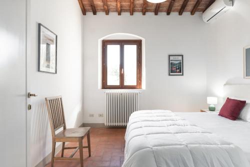 a white bedroom with a large bed and a chair at Bolgheri Countryhouse in Bolgheri