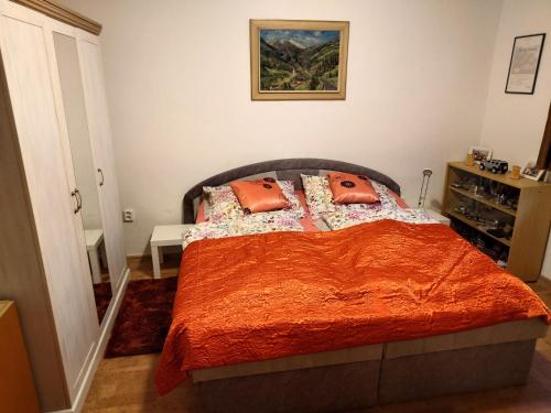 a bedroom with a bed with orange sheets and pillows at Apartmán Zukalka in Vítkovice