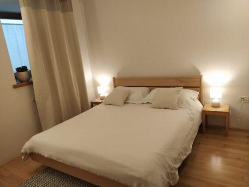 1 dormitorio con 1 cama blanca grande y 2 lámparas en Apartment Kenda, en Bovec