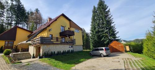 a car parked in front of a yellow house at Penzion na Lůkách in Horní Bečva