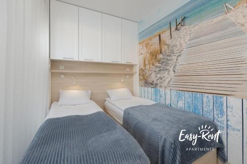 two beds in a room with a painting on the wall at Blue BIEN Easy - Rent Apartments z widokiem na morze in Rewal