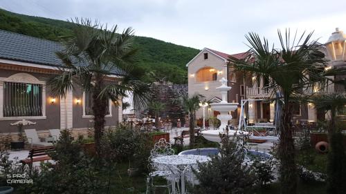 a courtyard with palm trees and a table and chairs at Museum Guest House-Muzey Ailəvi Qonaq Evi in Sheki