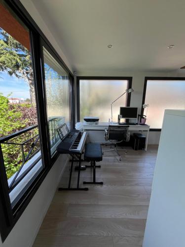 een kantoor met een piano en een bureau met ramen bij Sweet Home LR in Le Raincy