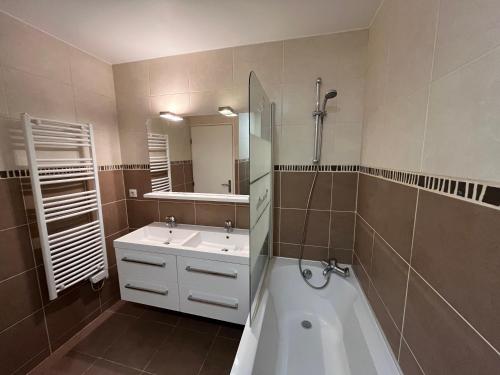 een badkamer met een bad, een wastafel en een spiegel bij Sweet Home LR in Le Raincy