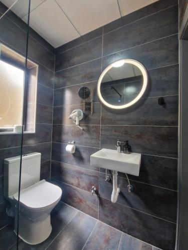 a bathroom with a toilet and a sink and a mirror at KORZO SUITES SENGLEA WATERFRONT in Senglea