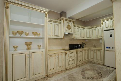 La cuisine est équipée de placards blancs et d'un réfrigérateur blanc. dans l'établissement "Bo'gishamol Gavhari" ООО, à Andijan