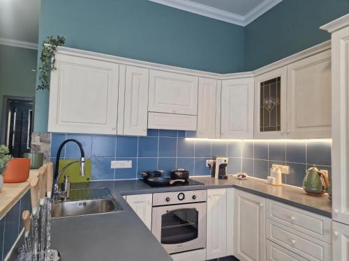 a kitchen with white cabinets and a sink at KORZO SUITES SENGLEA WATERFRONT in Senglea