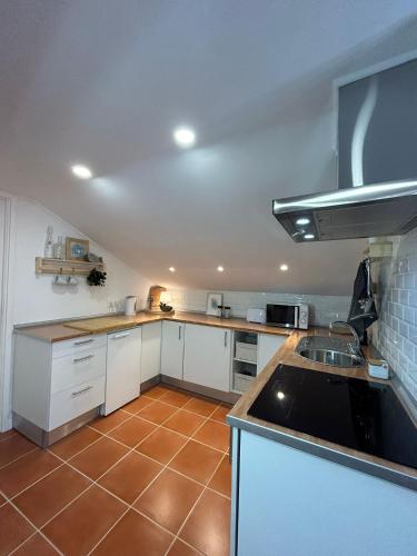 a kitchen with white cabinets and a brown tile floor at Refúgio do Seixal in Seixal