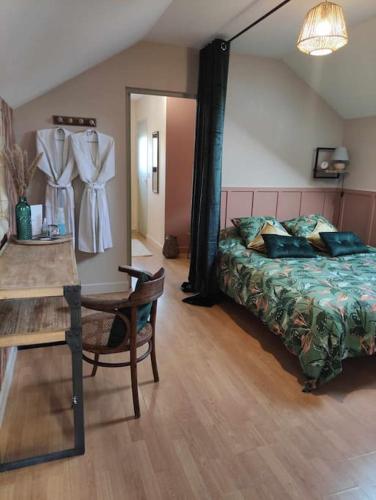 a bedroom with a bed and a table and a table and chair at Aux Alcôves du Spa in La Rothière