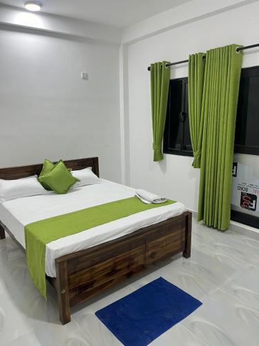 a bedroom with a large bed with green curtains at Krishna Bhavan Hotel in Trincomalee