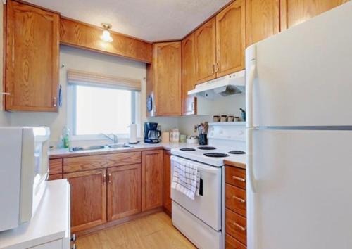 a kitchen with a white refrigerator and wooden cabinets at Home Away from Home - Guest Suite 1 in Red Deer
