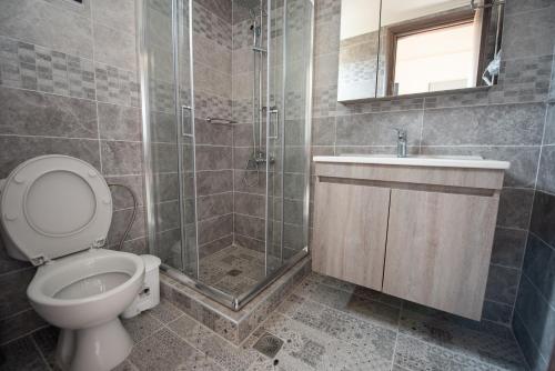 a bathroom with a toilet and a shower and a sink at Oasis Apartments in Kalliópi