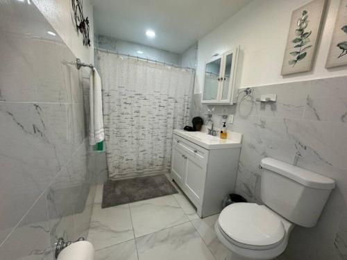 a white bathroom with a toilet and a shower at Brickell + Wynwood Wonderland: Spacious 6BR Home in Miami