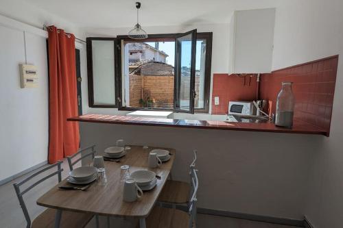 a kitchen with a wooden table with chairs and a window at Appartement intra-muros in Aigues-Mortes