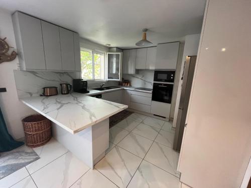 une cuisine avec des armoires blanches et un comptoir en marbre dans l'établissement Maison quartier parc de Tremblay, à Champigny-sur-Marne