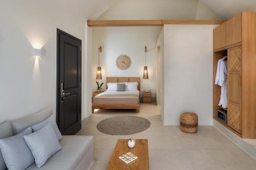 a bedroom with a bed and a couch and a table at Venus Sunrise Suites & Villas in Vourvoulos