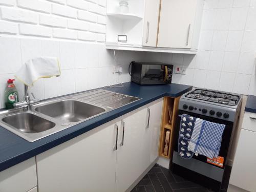 a small kitchen with a sink and a stove at 2 Bed House - Sleeps 4 - Pets - Garden - Parking in Bolton