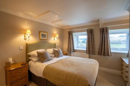 a bedroom with a large bed and two windows at The Pheasant Inn in Falstone
