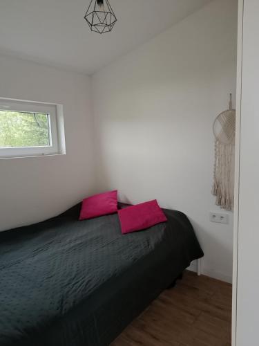 a bedroom with a black bed with two pink pillows at Między Jeziorami in Ogonki