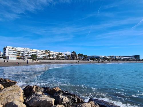 une plage avec des rochers dans l'eau et des bâtiments dans l'établissement Studio cosy front de mer à 5min de Nice, à Saint-Laurent-du-Var