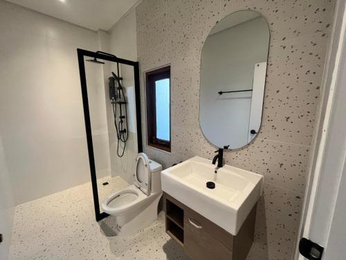 een badkamer met een wastafel, een toilet en een spiegel bij บ้านพูลวิลล่าอุดรธานี by บ้านแสนรัก in Udon Thani