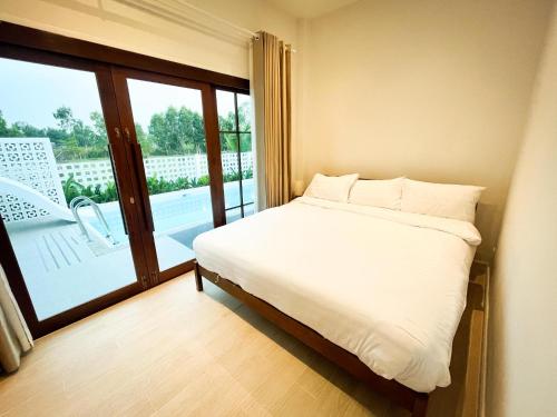 1 dormitorio con cama y ventana grande en บ้านพูลวิลล่าอุดรธานี by บ้านแสนรัก, en Udon Thani