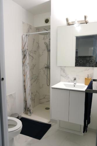 une salle de bain blanche avec une douche et un lavabo dans l'établissement Studio cosy front de mer à 5min de Nice, à Saint-Laurent-du-Var