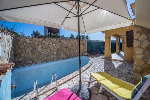 een patio met een parasol en stoelen en een zwembad bij Ferienhaus mit Privatpool für 7 Personen ca 100 qm in Castiadas, Sardinien Sarrabus Gerrei in Olìa Speciosa
