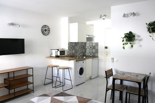 a kitchen with white walls and a table and chairs at Studio cosy front de mer à 5min de Nice in Saint-Laurent-du-Var