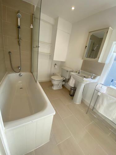 a bathroom with a tub and a toilet and a sink at A charming and stylish country cottage. in Hungerford