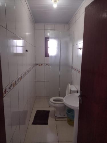 a white bathroom with a toilet and a sink at Hotel dos viajantes in São Gabriel