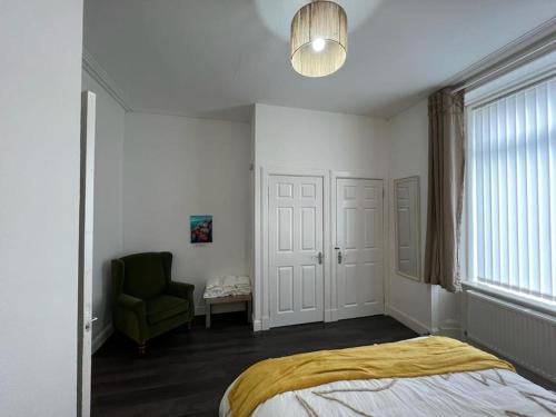 um quarto com uma cama e uma cadeira verde em Perfect Ardrossan 1-bed flat. 5 min to north beach. em Ardrossan