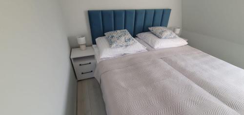 Apartamenty Łeba في ليبا: غرفة نوم مع سرير مع اللوح الأمامي الأزرق والوسائد