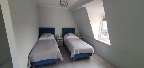 Apartamenty Łeba في ليبا: سريرين في غرفة صغيرة مع نافذة