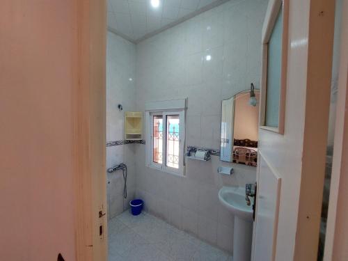 een witte badkamer met een wastafel en een spiegel bij Vintage Palace in Ksar es Sghir