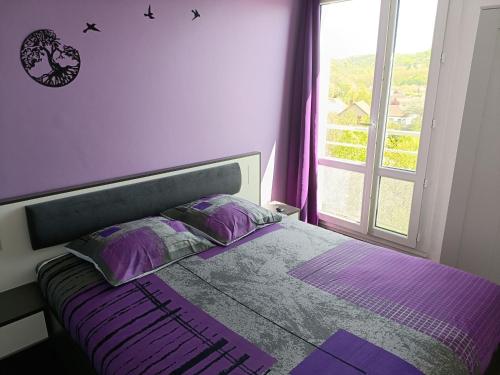 - une chambre avec un lit doté de draps violets et une fenêtre dans l'établissement Centre, appartement 6 voyageurs, à Montluçon