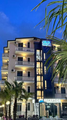 a building with palm trees in front of it at Apartments Costa Azzurra in Velipojë