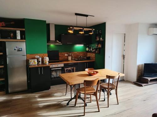 d'une cuisine avec une table en bois et des murs verts. dans l'établissement La porte de Paris, à Rosny-sous-Bois