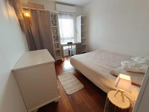 - une petite chambre avec un lit et une table avec une lampe dans l'établissement La porte de Paris, à Rosny-sous-Bois