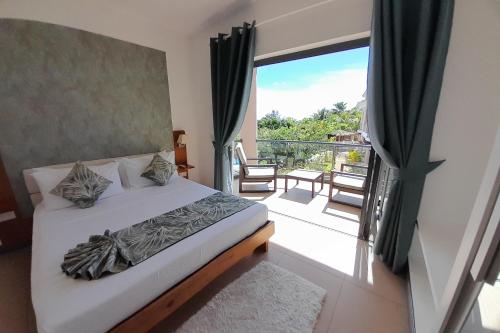 sypialnia z łóżkiem i balkonem w obiekcie ISLA HOLIDAY HOME w mieście Anse Royale